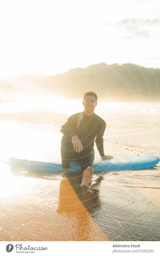 Man sitting on surfboard in beach man surfer sea sunset wave sport ocean water summer hobby male activity young sundown evening coast shore relax active sporty