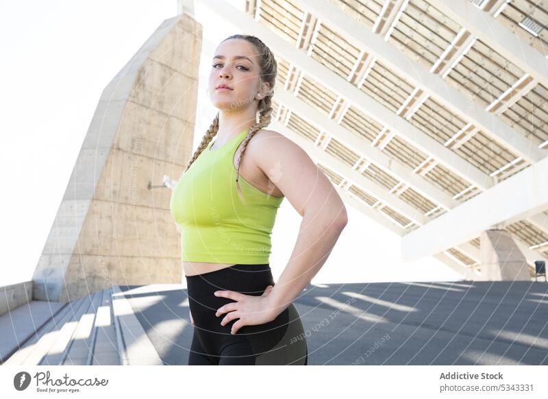 Sportswoman standing under solar panels in city athlete fit sportswear confident construction fitness workout hand on waist training sportswoman stair wellness