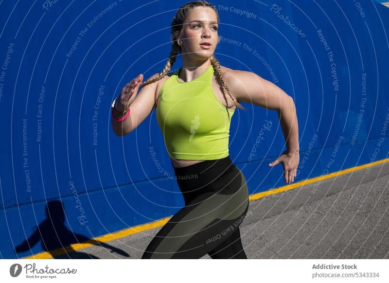 Strong sportswoman running and exercising near blue wall athlete workout stretch training exercise fit confident healthy fitness young sportswear wellness