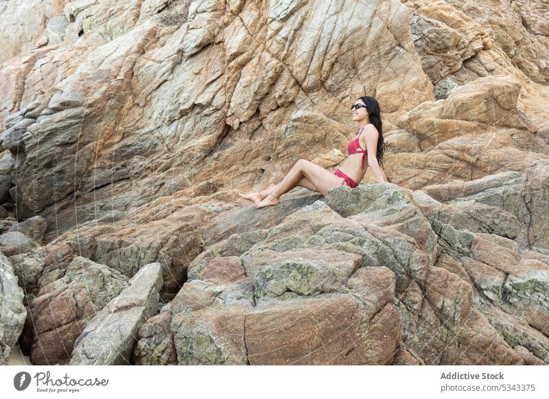 Smiling woman in bikini sitting on rocky cliff traveler happy tourist smile hill cheerful vacation summer adventure female puerto escondido oaxaca mexico