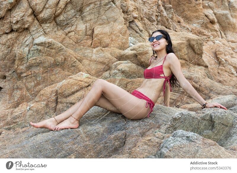 Smiling woman in bikini sitting on rocky cliff traveler happy tourist smile hill cheerful vacation summer adventure female puerto escondido oaxaca mexico