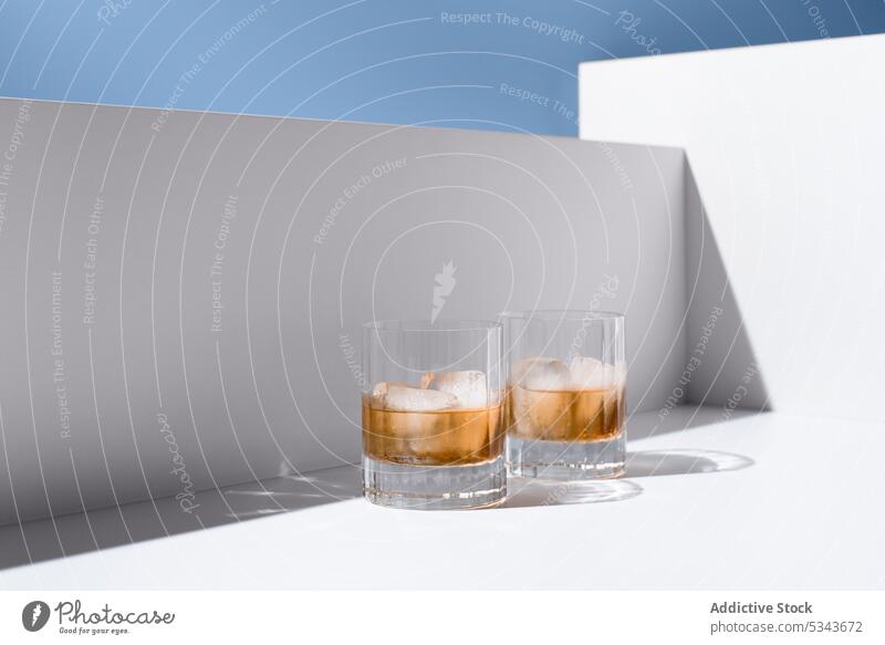 Glasses of refreshing scotch whiskey with ice cubes glass cold drink alcohol refreshment crystal clear liquid translucent transparent serve cool clean shadow