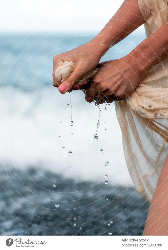 Crop woman wringing dress from water on beach sea shore coast tourist wave summer nature stone traveler trip vacation female journey ocean resort holiday