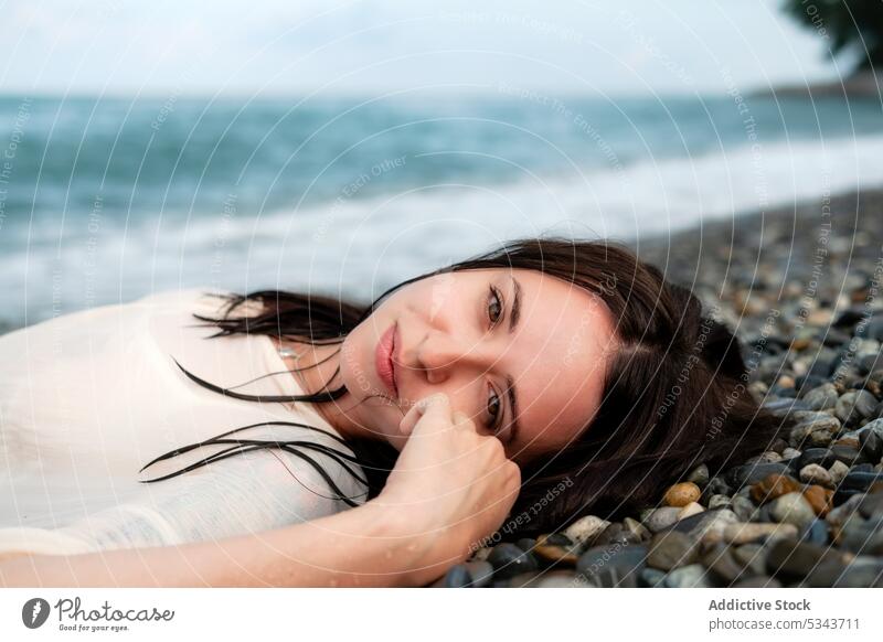 Charming woman lying on stony seashore summer rest vacation smile coast wave happy beach ocean positive relax female stone water young cheerful carefree travel