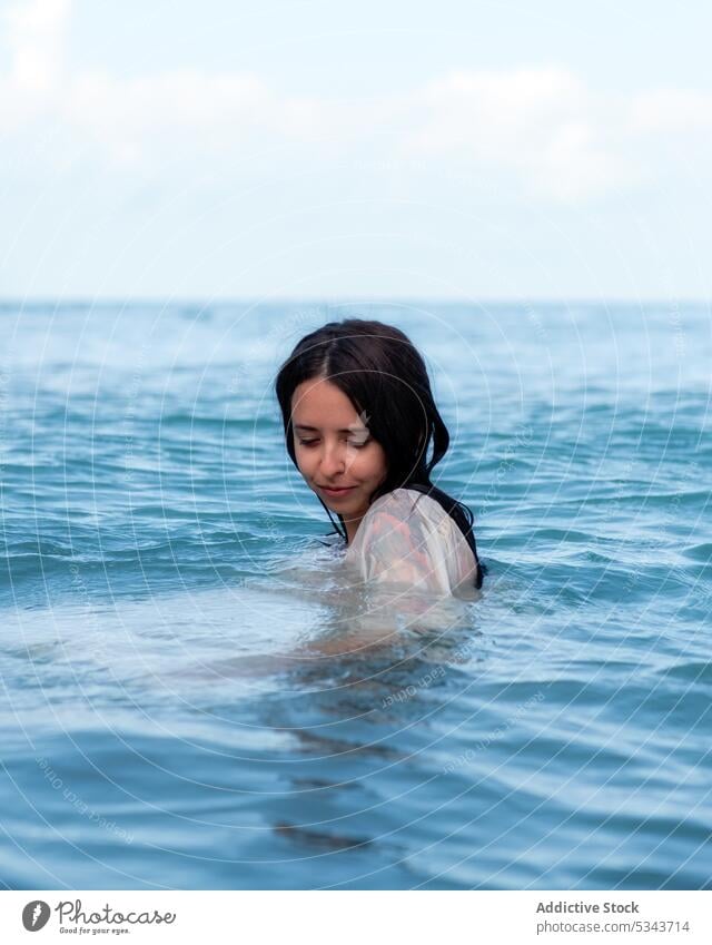 Content woman swimming in rippling sea summer vacation calm tranquil resort holiday blue sky wet young recreation carefree serene water nature wet hair ocean