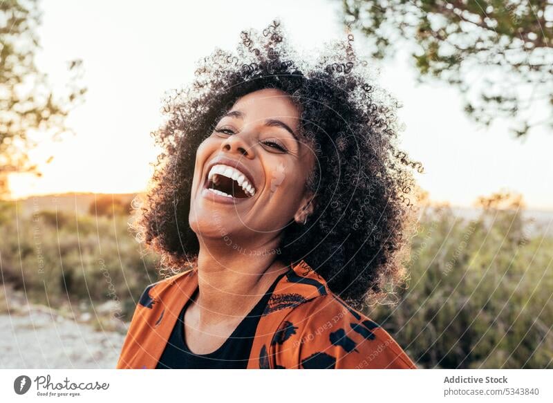 Cheerful black woman laughing in countryside cheerful positive portrait happy optimist curly hair expressive fun female african american ethnic smile joy grass