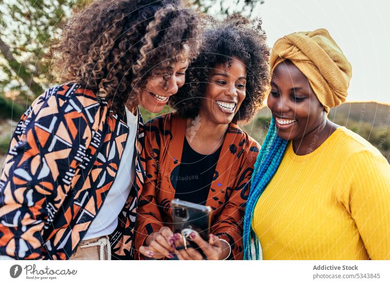 Cheerful diverse friends using smartphones together women cheerful browsing multiracial multiethnic smile style share female friendship happy young delight joy