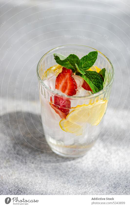 Summer cocktail with ice, mint and strawberry against blurred background beverage drink fresh glass leaves lemon organic ripe season seasonal served shadow
