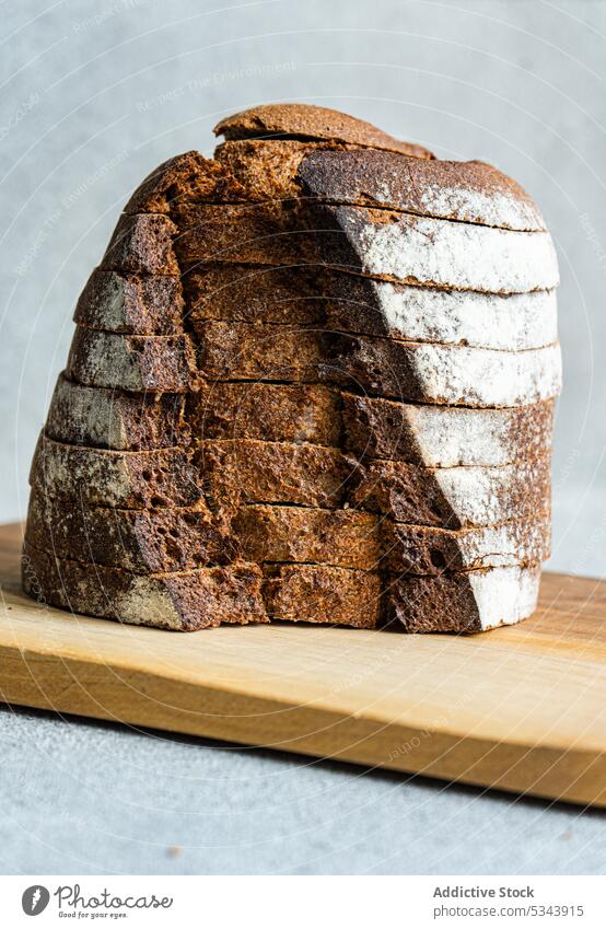 Front view of stack of rye bread slices on wooden cutting board against blurred light background eat eating food healthy organic plant based sour dough bakery