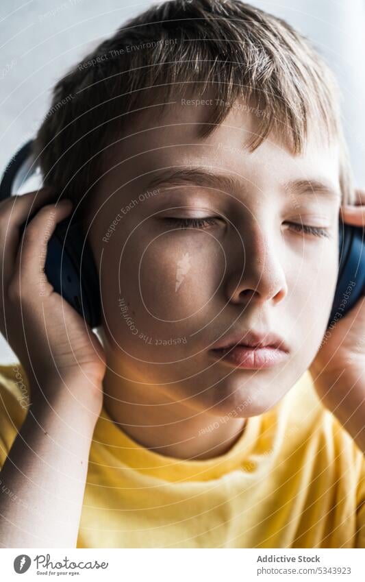 Portrait of serious closed eyes kid with listening to music beautiful boy child ear face headphones human over-ear person portrait t-shirt teenager tunes