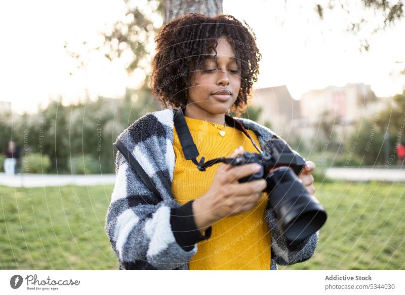 Black woman standing with photo camera in park photographer professional take photo lawn photography focus concentrate cityscape street female device hobby