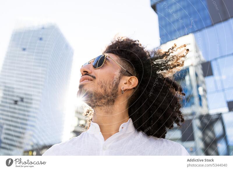 Smiling ethnic man with glasses looking at the sky young browsing trendy street city masculine sunglasses using device male black african american style outfit