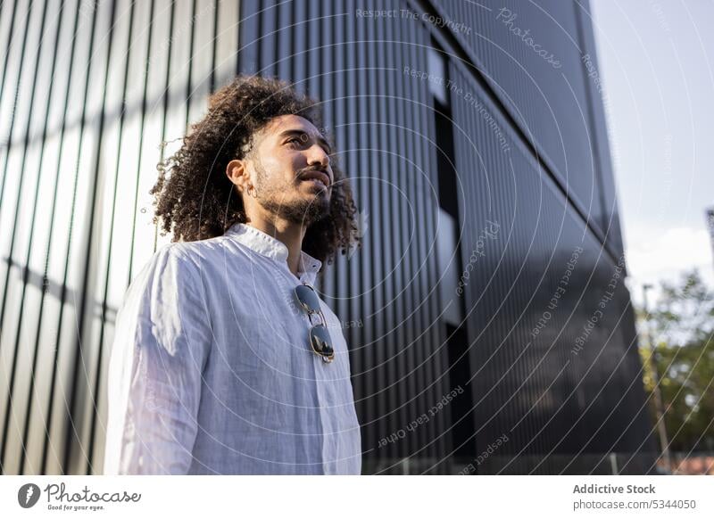 Happy ethnic man walking in the city street confident pensive afro gadget male african american black modern casual style using urban device black man