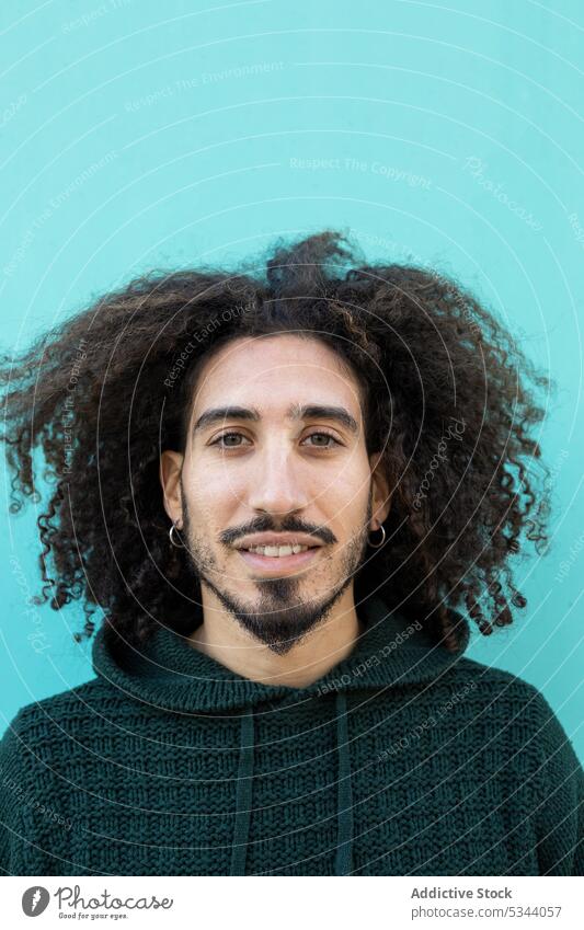 Happy black man with curly hair on blue background smile positive portrait individuality personality studio sweater appearance male glad african american happy