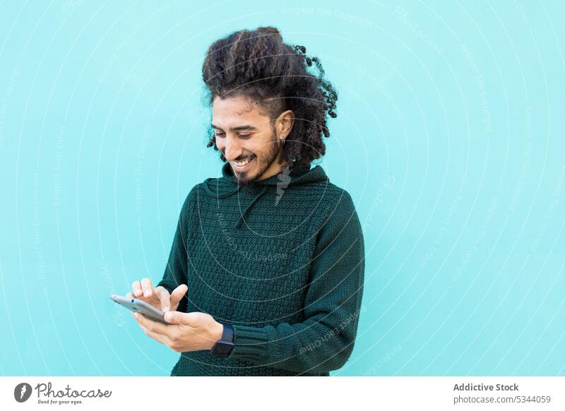 Cheerful black man using smartphone message browsing african american ethnic confident afro appearance outfit cellphone gadget cool device modern male