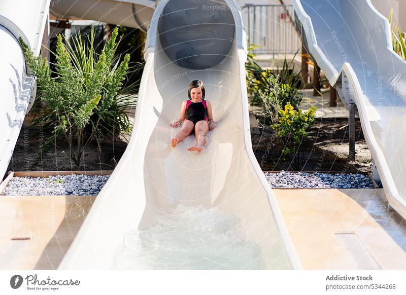 Funny girl sliding on water slide resort holiday pool rest summer vacation weekend tropical hotel kid child activity childhood fun cheerful chill tourism travel