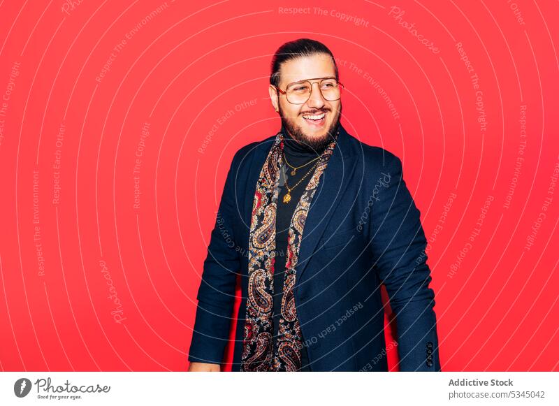 Rich and cheerful man looking away on a red studio portrait rich mafia luxury confident self assured fashion hands clasped outfit suit smiling young