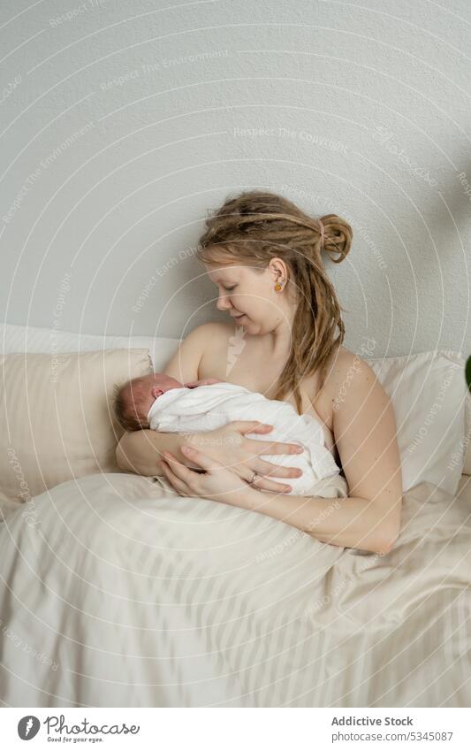 Mother breastfeeding newborn on bed woman mother baby infant mom childcare maternal cozy female comfort innocent motherhood together bedsheet lady peaceful