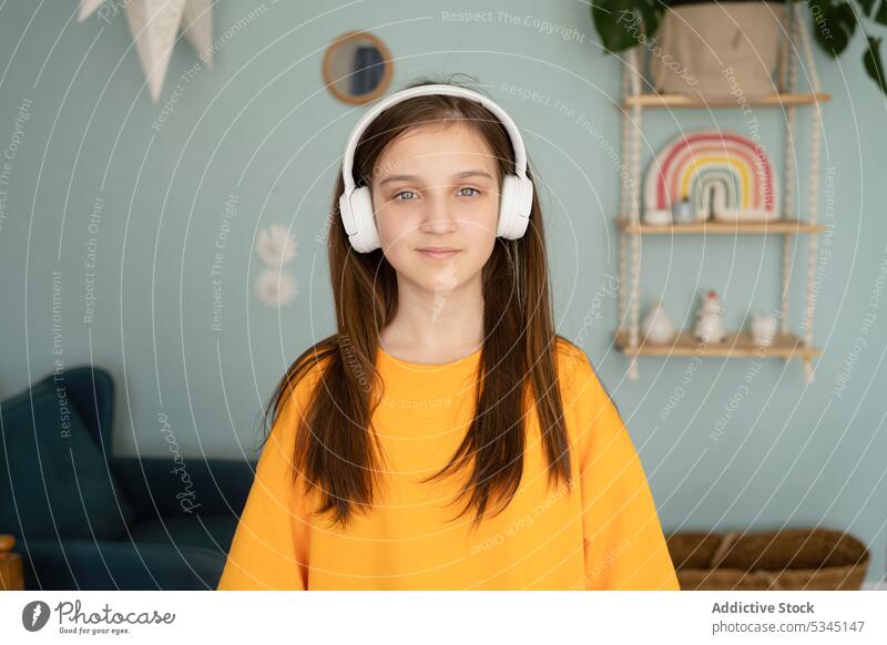 Thoughtful child in headphones listening to music girl portrait bedroom using gadget thoughtful modern serious meloman wireless long hair casual appearance