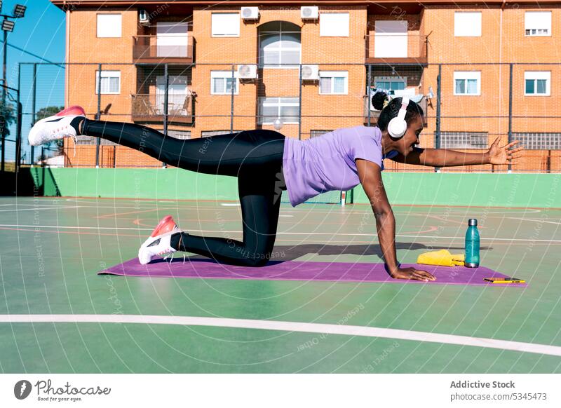 Fit African American sportswoman listening to music while training in park exercise workout fitness healthy wellness strong sports ground female adult