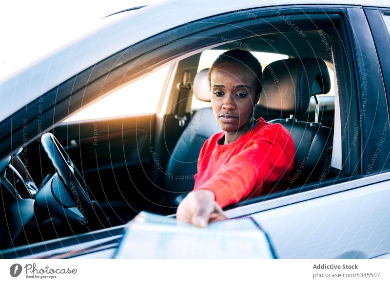 Sad young woman on driver seat showing documents license car steer automobile stop serious sad female paper check identification transport vehicle safe road