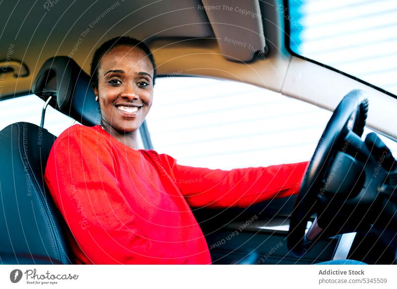 Smiling ethnic lady looking at camera in car woman smile driver vehicle content cheerful automobile confident positive glad female african american black adult