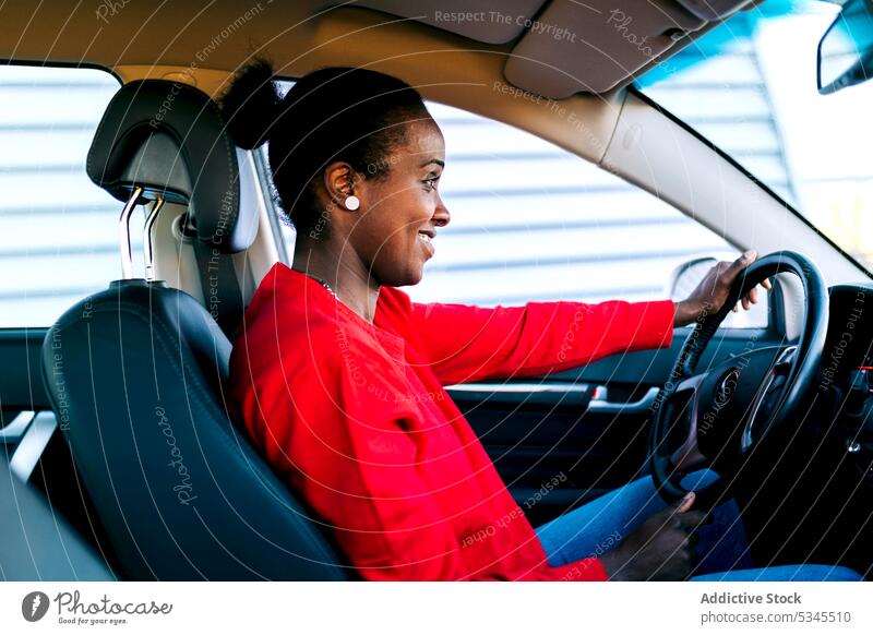 Smiling ethnic lady while driving a car woman smile driver vehicle content cheerful automobile confident positive glad female african american black adult