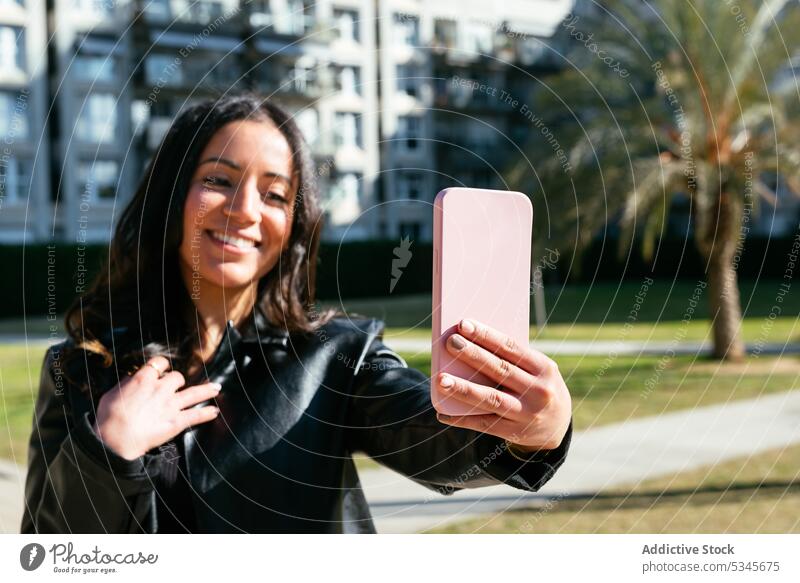 Happy ethnic woman taking a selfie smartphone using street urban text message online internet connection young female gadget device cellphone happy surfing