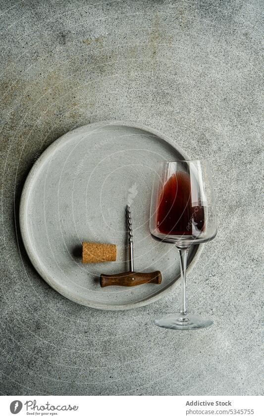 High angle of glass of red dry wine in glass lying on a plate with a corkscrew and a cork on concrete background Kisi alcohol beverage drink fresh georgia