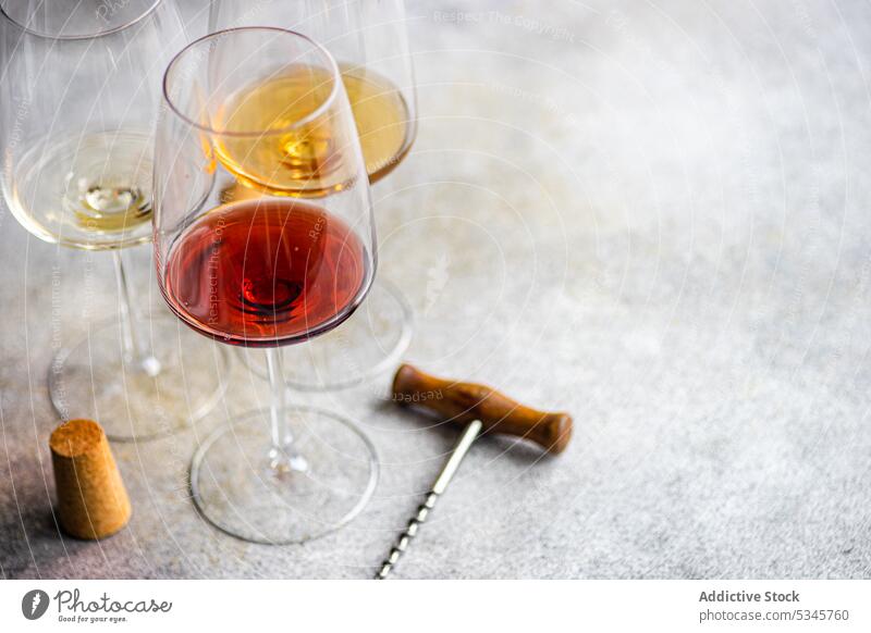 High angle of three main varieties of Georgian dry wines - white, red and amber on concrete grey table with a corkscrew and a cork Kisi alcohol background