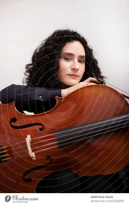 Woman with cello in music studio woman musician serious instrument portrait calm skill melody female curly hair hobby casual sit confident concentrate pensive