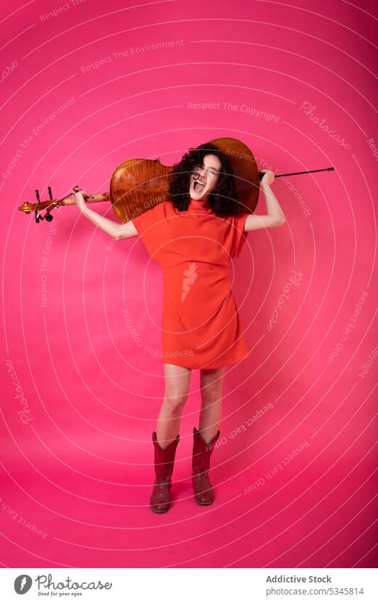 Stylish woman with cello in pink studio trendy excited elegant acoustic colorful musician style fashion instrument vivid bright studio shot sound talent