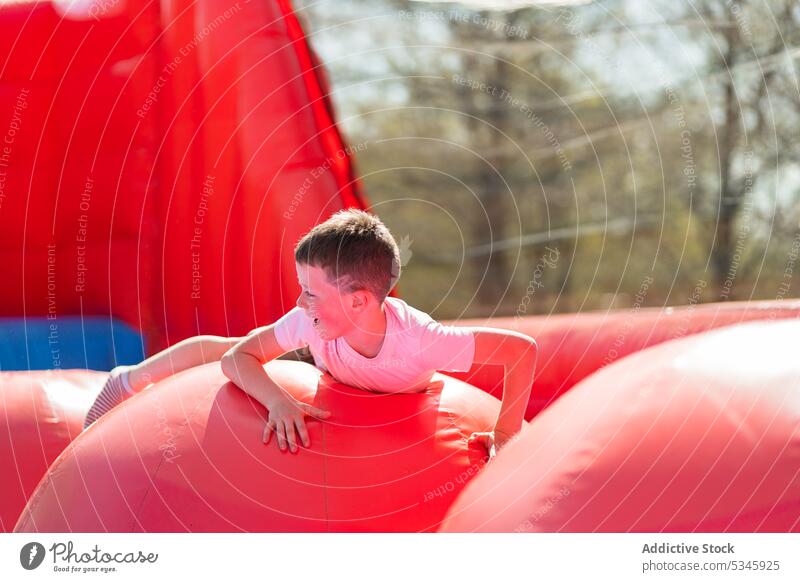 Smiling child lying on bouncy house kid smile summer colorful happy adorable delight inflatable boy cheerful bright tree joy positive daytime childhood fun