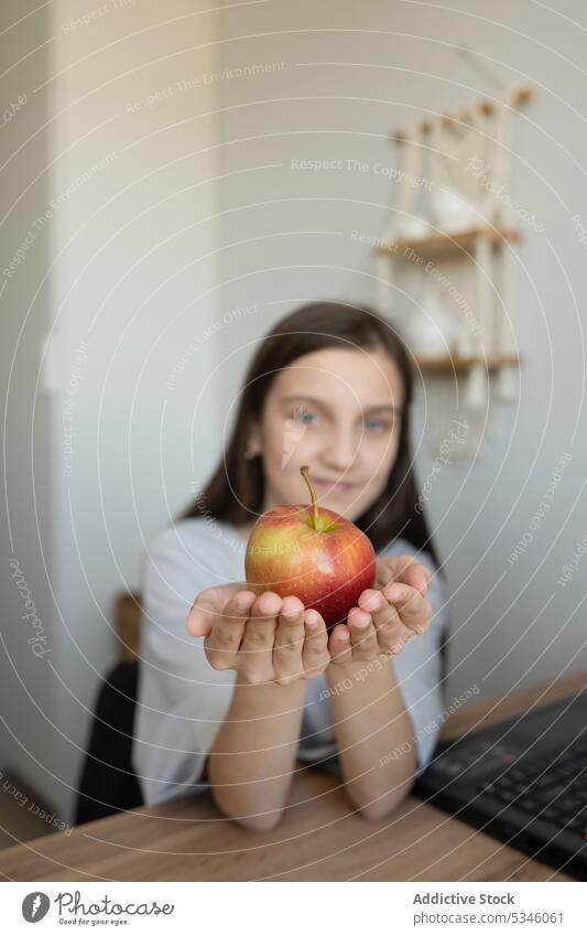 Girl with apple sitting at working table girl snack positive teenage education home smile study desk workspace casual adolescent fruit healthy food student