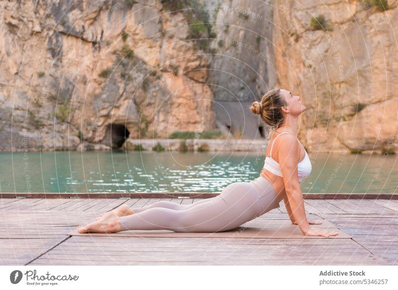 Flexible woman practicing yoga asana outdoors practice slim stretch wellness Charco Azul zen cobra pose lake mountain activewear nature female harmony