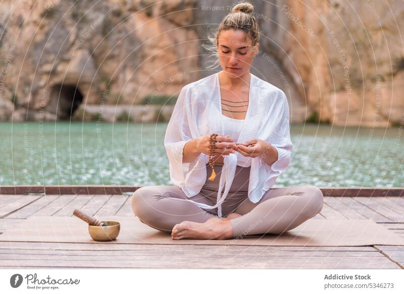 Woman practicing yoga near mountain lake woman meditate singing bowl pier Charco Azul stress relief Valencia Spain concentrate zen practice wellness spirit