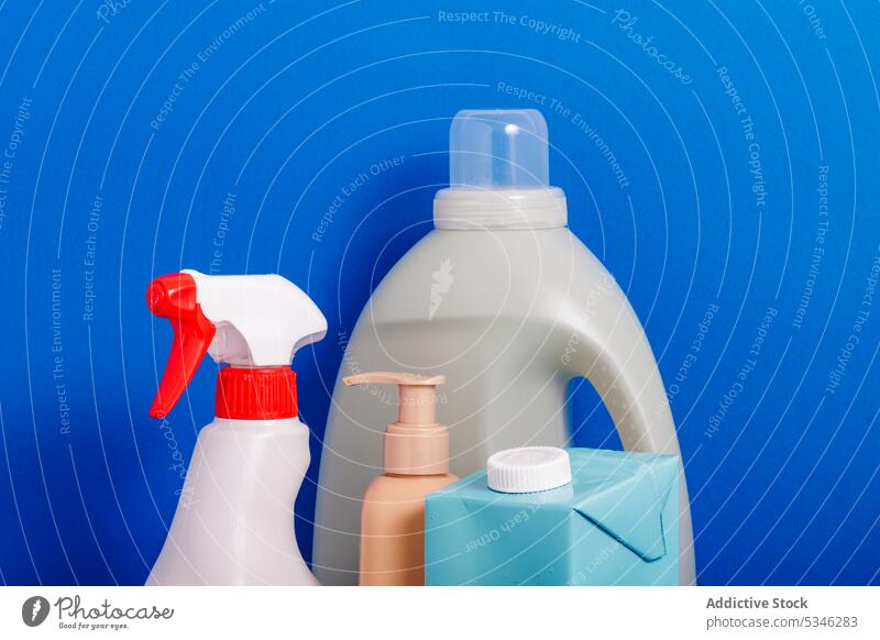 Generative AI illustration of different cleaning supplies in plastic bottles and dispensers on blue background representing concept of recycling packaging