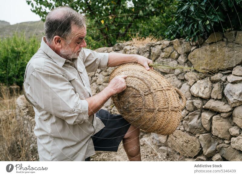 Serious mature male artisan checking wicker basket on farm man esparto grass craft countryside examine concentrate master tradition stipa tenacissima