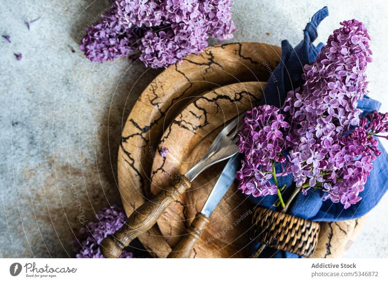 Spring table setting with lilac flowers on brown tableware against grey background bloom blossom color colorful concrete cutlery dinner dinnerware eat petal