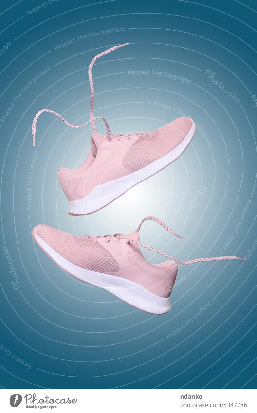 Pink women's sports sneakers with laces levitate on a blue background shoelace fitness fly new wear pair sporty supportive training trendy workout casual