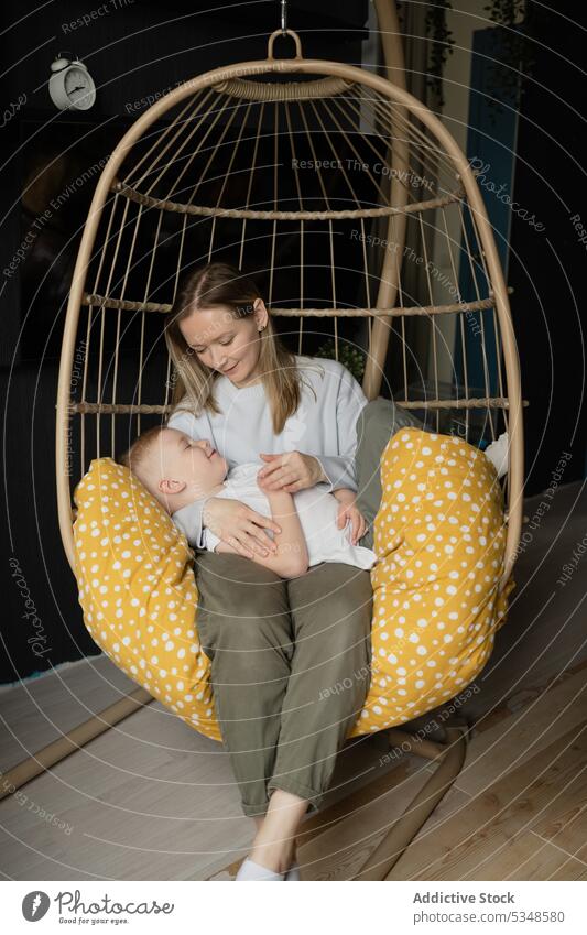 Mother with sleeping son in hanging chair mother relax rest love care woman together bonding nap kid boy comfort casual asleep calm sit lap motherhood parent