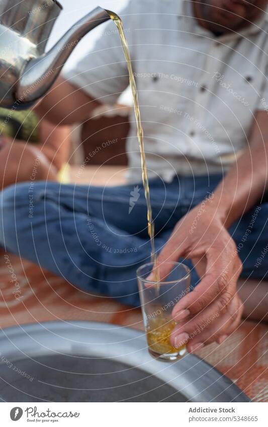 Cropped male pouring hot tea into glass man refreshment beverage local casual sit glassware tradition serve marrakesh morocco hot drink chill cafe liquid alone