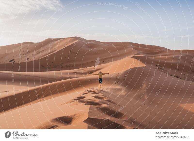 Unrecognizable traveler standing on top of desert sand man dune explore freedom admire nature landscape person journey wanderlust desolate climate exotic