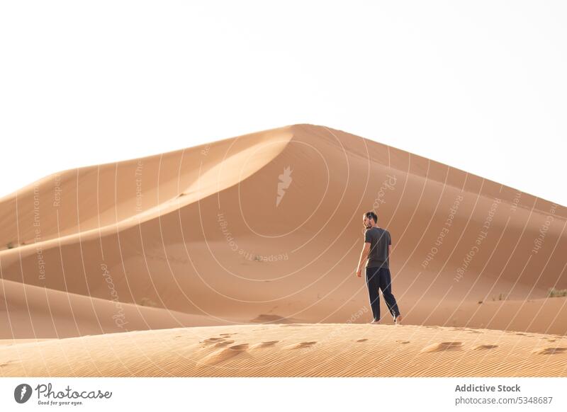 Man standing on sandy terrain person traveler desert dune tourist dry sky summer trip cloudless marrakesh morocco walk city nature landscape tourism building
