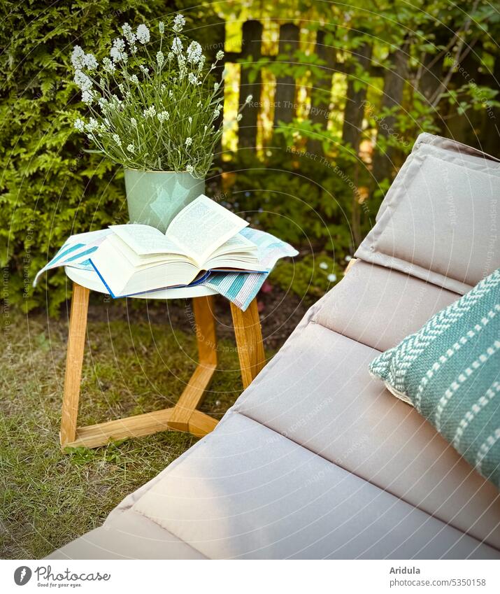 Favorite place | lounger with cushion stands in the garden, next to it is a table on which lies an open book, behind it is a white lavender in a pot Garden