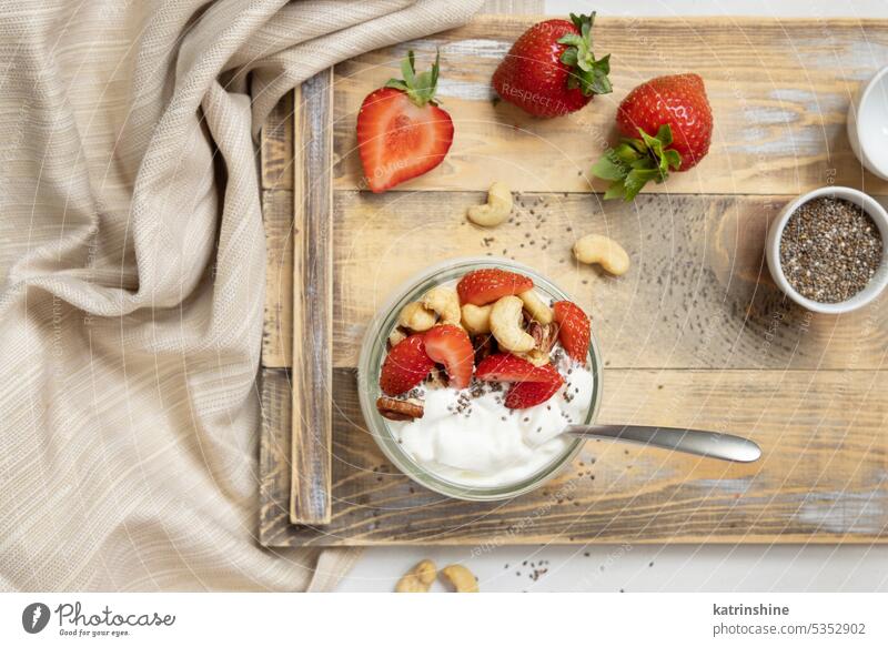 Glass jar of yogurt, nuts and strawberries on a wooden tray  top view, copy space breakfast spoon Healthy fruits Greek eat protein glass red food organic