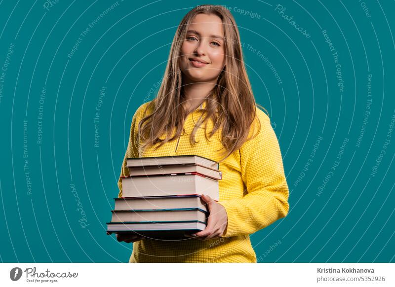 Smiling adult student woman with stack of books from library on blue background american arms attractive beautiful casual clever college conception difficulty