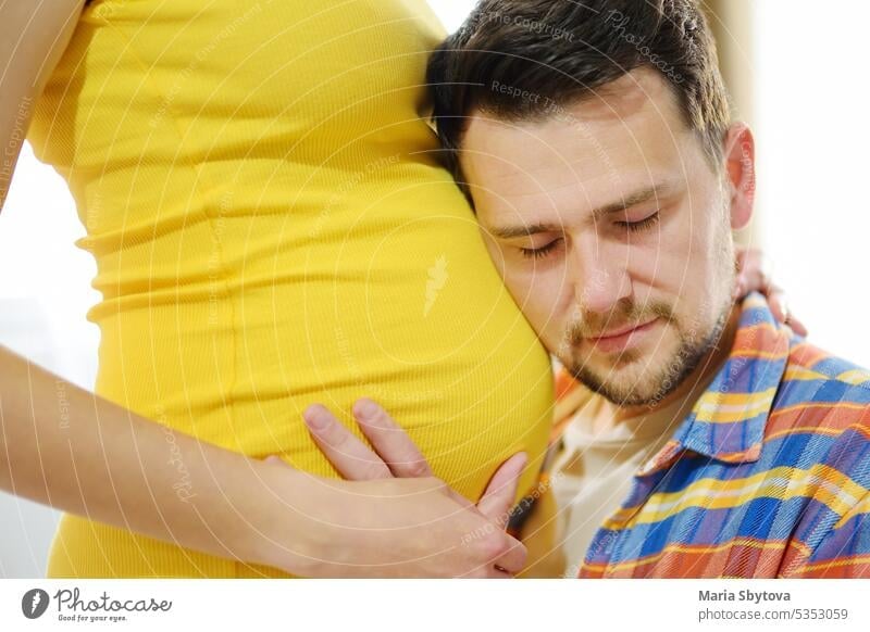 Young family is expecting a baby. Handsome man touching the belly of pregnant woman and feeling the movements of the child. future dad father couple girl tender