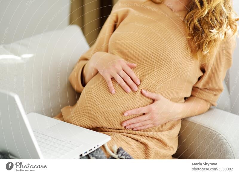 Pregnant woman works at a computer in a home office. Expectant mother searches for information on the Internet or makes online purchases of baby goods. pregnant
