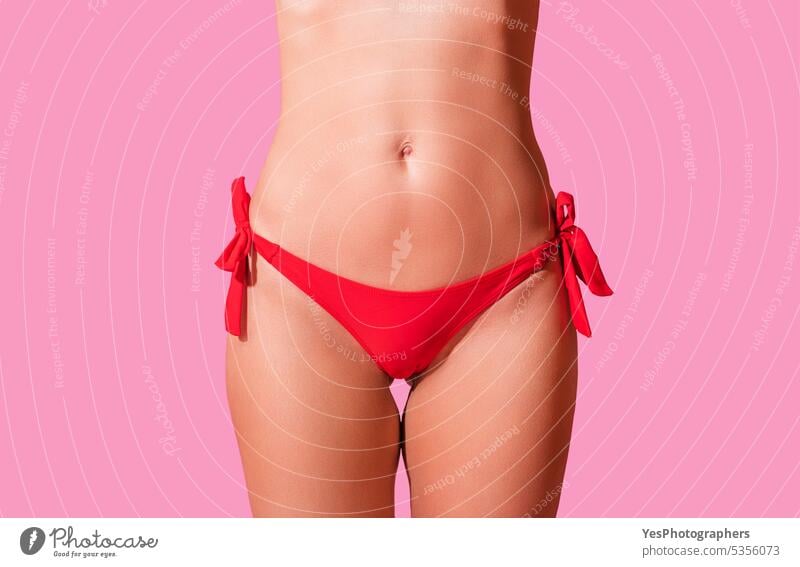 Red bikini woman's waist isolated on pink background. Mature woman fit body  - a Royalty Free Stock Photo from Photocase